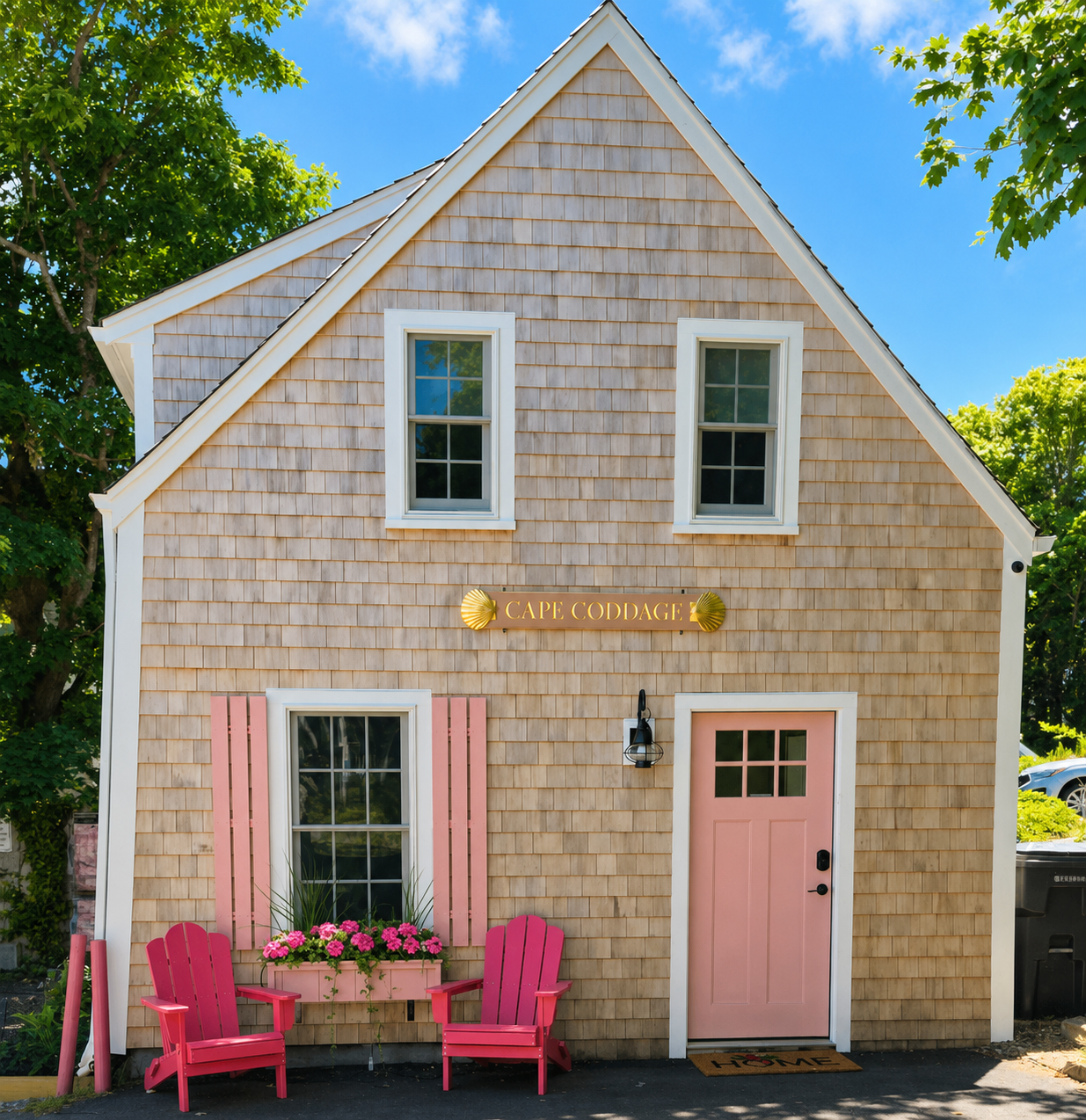 Cape Coddage — full front of building with vibrant window box, pink door and Adirondack chairs